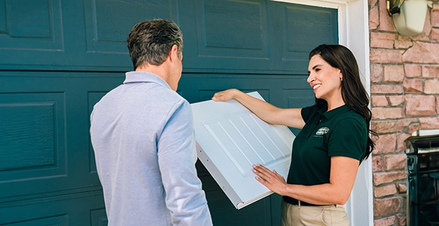 A Precision Garage Door Service technician showing a customer schematics in front of a garage.