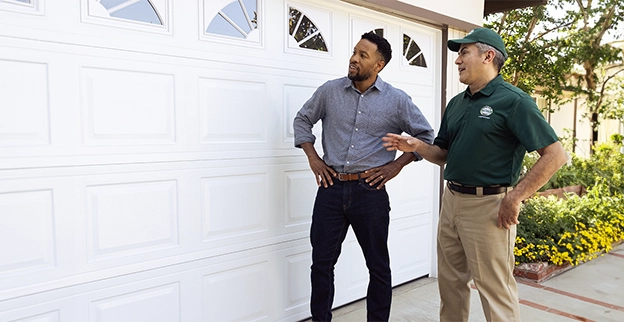 Precision Garage Door Service technician talking with a customer in front of their garage.
