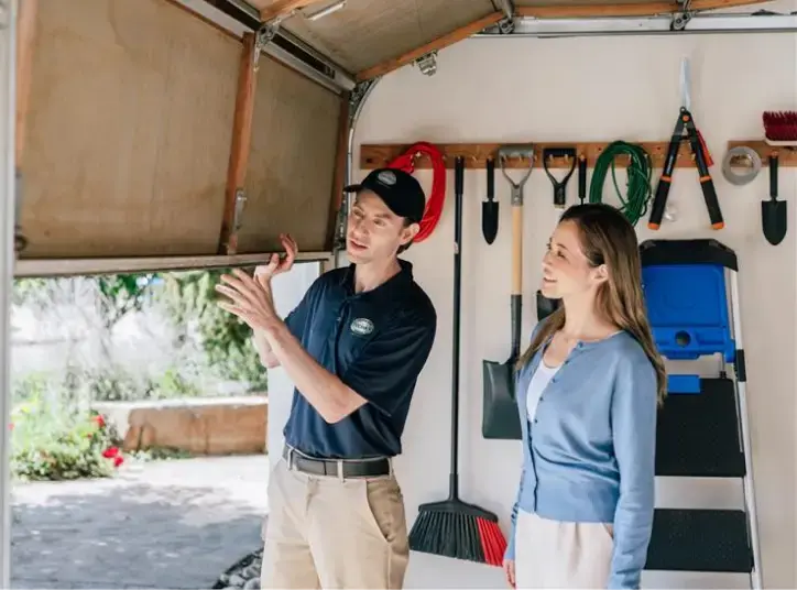 Garage door technician discussing garage door maintenance with homeowner.