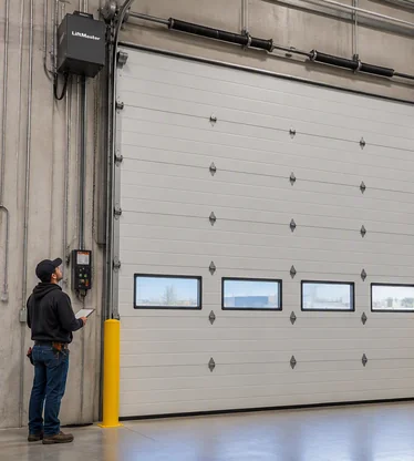Precision Door technician looking at warehouse garage door.