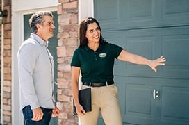 A PDS expert explaining to a client in front of a green garage door.