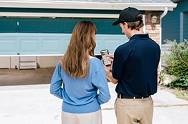 A PDS expert explaining to a client about a smart wi-fi opener in front of a garage door.