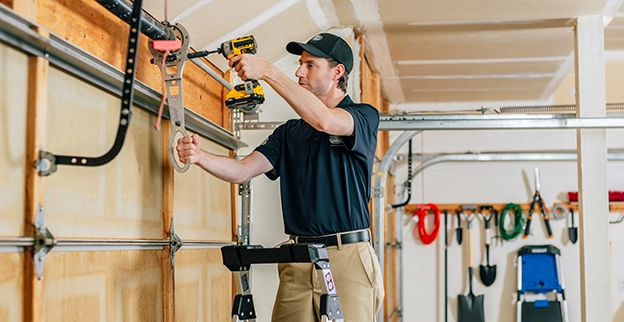 A PDS expert on a ladder drilling into the garage door.