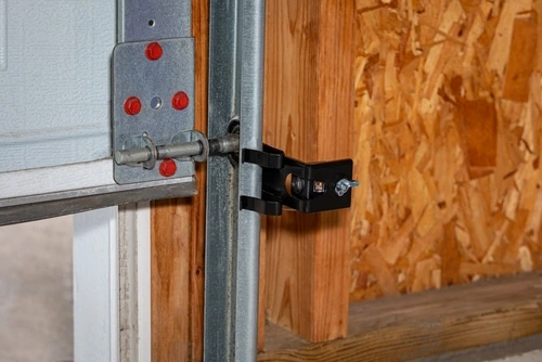 Overhead garage door opener safety sensor installed on roller track.