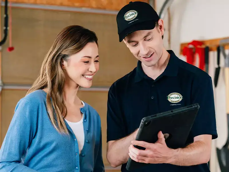 A Precision Garage Door Service professional and a customer look at a plan for a garage door tune-up together.