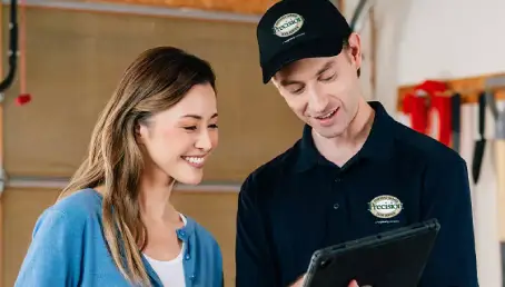 A Precision Garage Door Service professional and a customer look at a plan for a garage door tune-up together.