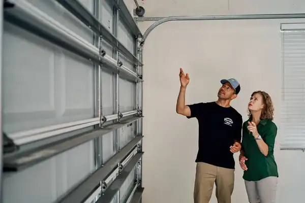 A Precision Garage Door service professional explaining the features of a sectional garage door to a homeowner.