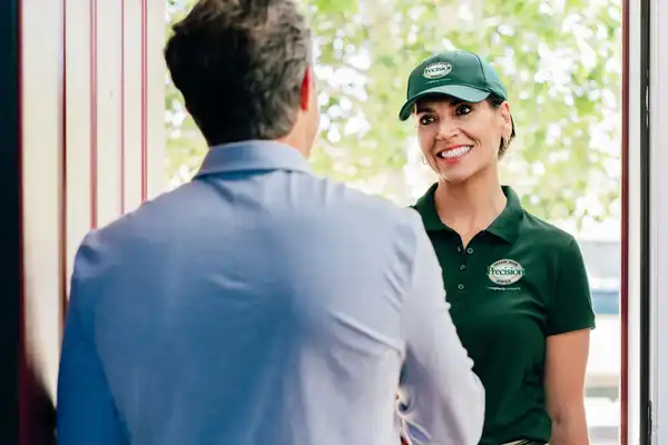 A Precision Garage Door service professional greets a homeowner at the door.
