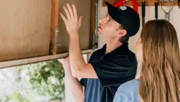 A Precision Garage Door Service professional examining a garage door with a customer.