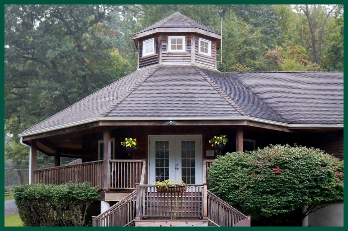 Grey house with wrap-around front porch.