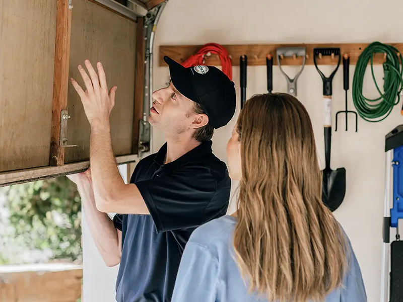 Precision Garage Door Service professional shows a customer their garage door after lubricating it.