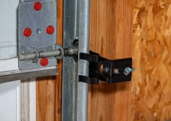 Overhead garage door opener safety sensor installed on roller track.