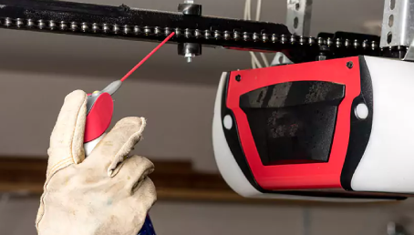 Garage door professional lubricating a chain garage door opener.